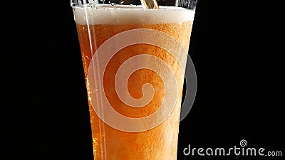 La cerveza está vertiendo en un vidrio en fondo negro La cerveza está vertiendo en un vidrio en fondo negro