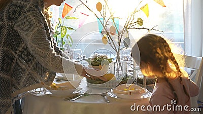La donna e la sua piccola figlia stanno mettendo la tavola festiva di pasqua con il coniglietto ed eggs la decorazione stock footage La donna e la sua piccola figlia stanno mettendo la tavola festiva di pasqua con il coniglietto ed eggs la decorazione stock footage