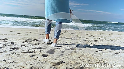 La femelle méconnaissable dans le manteau bleu astucieux, les jeans et les chaussures seul marchent sur la plage de sable blanc a clips vidéos La femelle méconnaissable dans le manteau bleu astucieux, les jeans et les chaussures seul marchent sur la plage de sable blanc a clips vidéos
