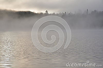 La Mauricie National Park Wapizagonke lake early in the morning. Fog in the morning above lake with tree line in the far. Stock Photo