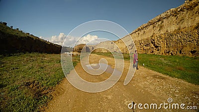La muchacha camina a lo largo de un camino de tierra en una fosa profunda de la fortaleza medieval de Famagusta metrajes La muchacha camina a lo largo de un camino de tierra en una fosa profunda de la fortaleza medieval de Famagusta metrajes
