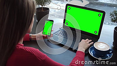 La muchacha en el café trabaja con los artilugios con las pantallas verdes almacen de video La muchacha en el café trabaja con los artilugios con las pantallas verdes almacen de video