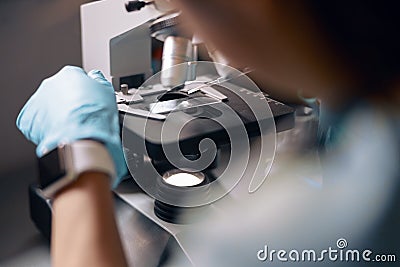 Lab assistant in gloves puts material sample onto slide at microscope working in laboratory Stock Photo