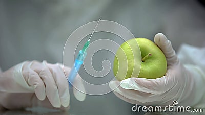 Lab researcher holding syringe and apple, gmo food production, experiment Stock Photo