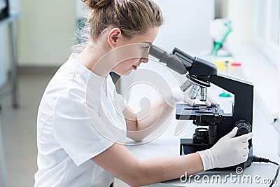 Lab technician looking through microscope Stock Photo