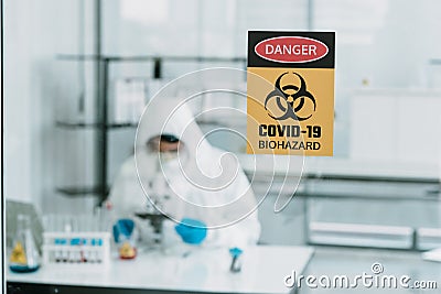 Notice Dangerous sign about covid-19 virus attached on Glass window of laboratory Stock Photo