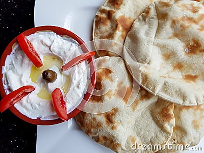 Labneh and tomatoes. Top view of a bowl of labneh, delicious and creamy yoghurt dip with flat bread. Middle eastern food Stock Photo