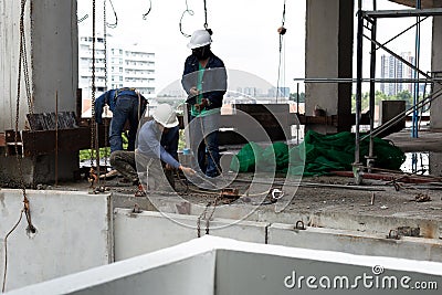 Labor man working on construction site with helmet pulling concrete slabs using pulley Editorial Stock Photo