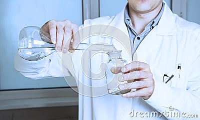 Laboratory assistant pours liquid from a flask. Stock Photo