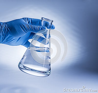 Laboratory beaker in analyst`s hand in plastic glove Stock Photo