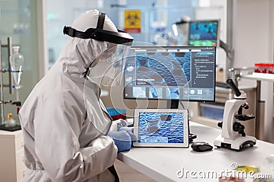 Laboratory chemist wearing ppe suit using tablet pc Stock Photo