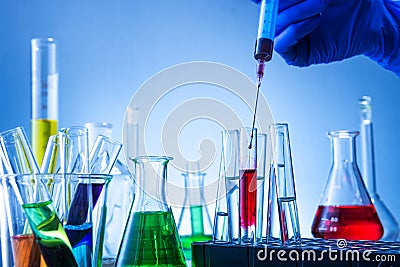 Laboratory equipment, lots of glass filled with colorful liquids and hand injection Stock Photo