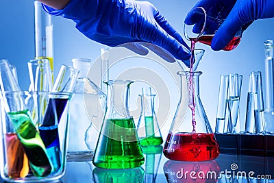 Laboratory equipment, lots of glass filled with colorful liquids, hand poured Stock Photo