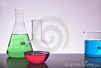 Laboratory glass chemical containers full on glass table gray ba Stock Photo