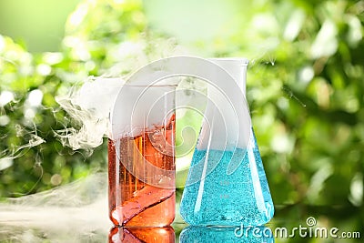 Laboratory glassware with colorful liquids on glass table outdoors. Chemical reaction Stock Photo