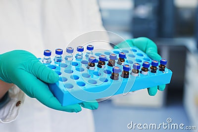 Laboratory scientist holds a plastic box with samples of transparent liquid in the vials. Stock Photo