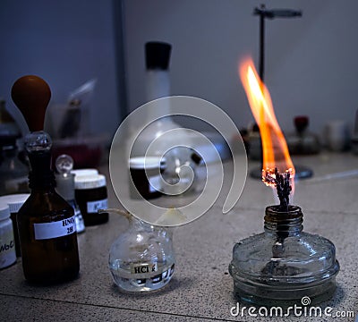 Laboratory table on which there are vials and a container with a burning wick. Stock Photo