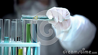 Laboratory worker adding liquid from test tube with poison symbol, life danger Stock Photo