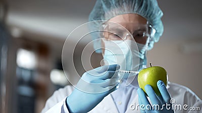 Laboratory worker injecting apple with chemicals, adding smell and juiciness Stock Photo