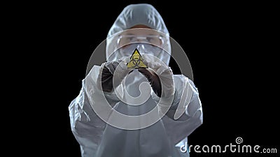 Laboratory worker in protective suit showing biological hazard symbol, weapon Stock Photo