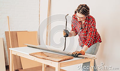 Laborer girl with crowbar in her hands pulls nails out of the board Stock Photo