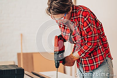 Laborer girl drilling plank with drill on the table Stock Photo