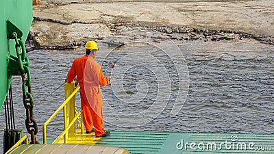 Labuan,Malaysia-July 29,2019:Crew worker in orange coveralls & wearing protective equipment helmet standing on edge of deck while Editorial Stock Photo