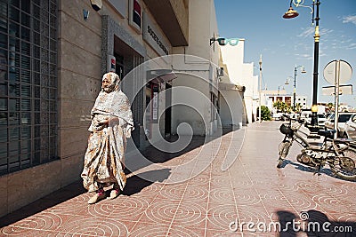 LAC ROSE, SENEGAL - JANUARY 18, 2020: Women walking down the street, wearing beautiful blue and white Arab clothes. Editorial Stock Photo