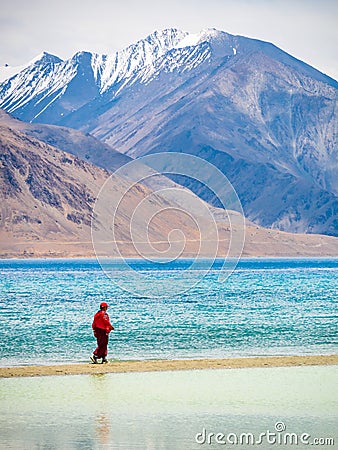 Unidentified buddhist monk walking near beautiful Pangong lake. Vertical or portrait orientation Editorial Stock Photo