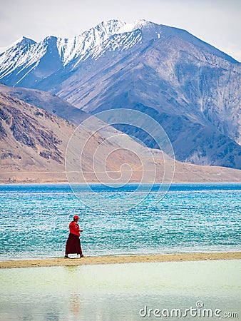 Unidentified buddhist monk walking near beautiful Pangong lake. Vertical or portrait orientation Editorial Stock Photo