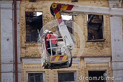 Ladder cart with the fire against the background of the facade of the burned building Editorial Stock Photo