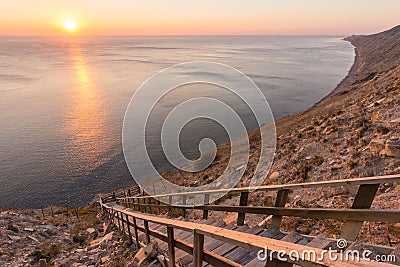 Ladder going down to the sea on a rocky cliff, sunset, Anapa, Russia Stock Photo