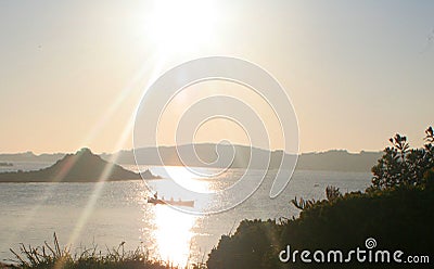 At sunset a rowing gig crosses the still silver waters off Tresco, isles of Scill,y Engla Stock Photo