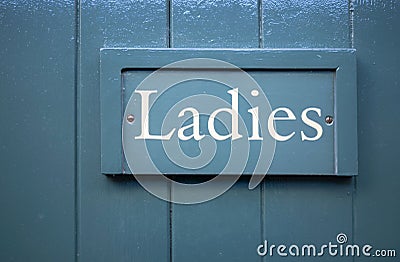 Ladies toilet sign written with white letters on a teal wooden door. Stock Photo