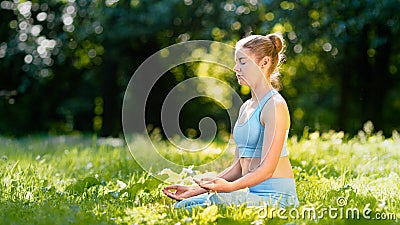Lady athlete in blue tracksuit practices yoga sitting in relaxation pose Stock Photo
