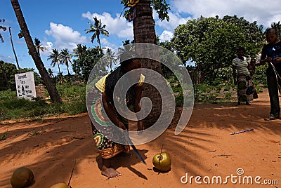 A lady bending with a big knife in front of a coconut Editorial Stock Photo