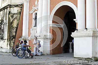 Lady, Blind Man beside disabled Beggar in wheelchair at Church yard Gate Portal Editorial Stock Photo