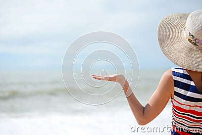 Lady in broadbrim hat facing sun standing on sandy Stock Photo
