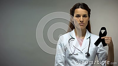 Lady doctor showing black ribbon, melanoma awareness, disease level, death rate Stock Photo