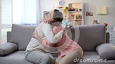 Lady embracing mother, senior woman holding gift box, pleasant surprise, care Stock Photo