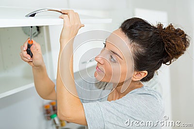 lady fitting handle on kitchen cupboard Stock Photo