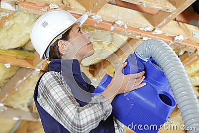 lady fitting ventilation hose into roof space Stock Photo