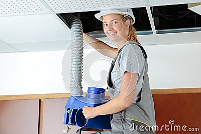 Lady fitting ventilation hose into roof space Stock Photo