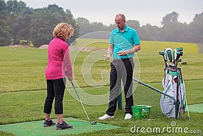 Lady golfer being taught by a golf pro. Stock Photo