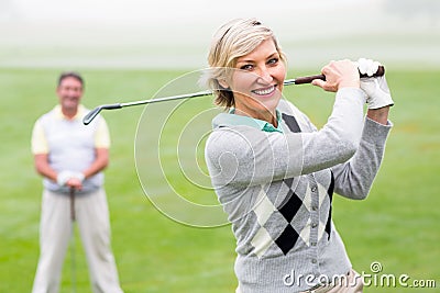 Lady golfer teeing off for the day watched by partner Stock Photo