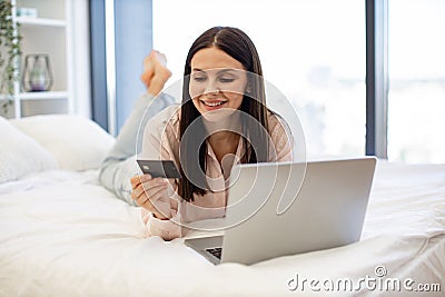 Lady lying on bed and enjoying purchase of goods on Internet using bank card. Stock Photo
