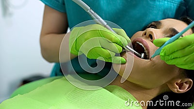 Lady patient sitting in stomatology chair, dentist drilling tooth, modern clinic Stock Photo