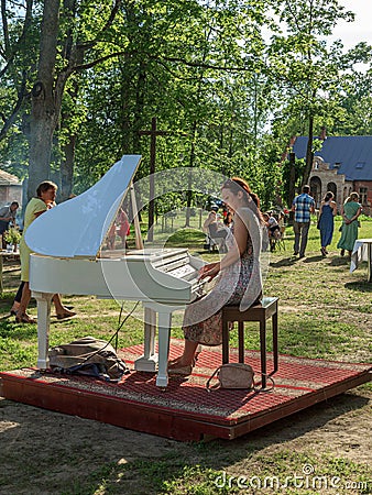 Lady playing white piano, village charity event Editorial Stock Photo