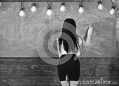 Lady teacher in short skirt with slit explaining formula. teacher concept. Teacher of mathematics writing on Stock Photo