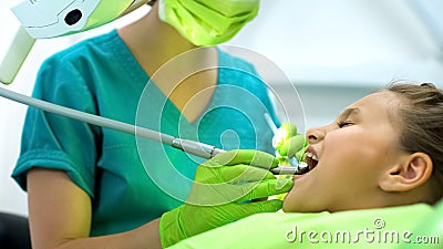 Lady stomatologist polishing little girls tooth enamel, oral cavity protection Stock Photo